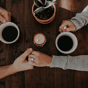 man and woman holding hands over coffee